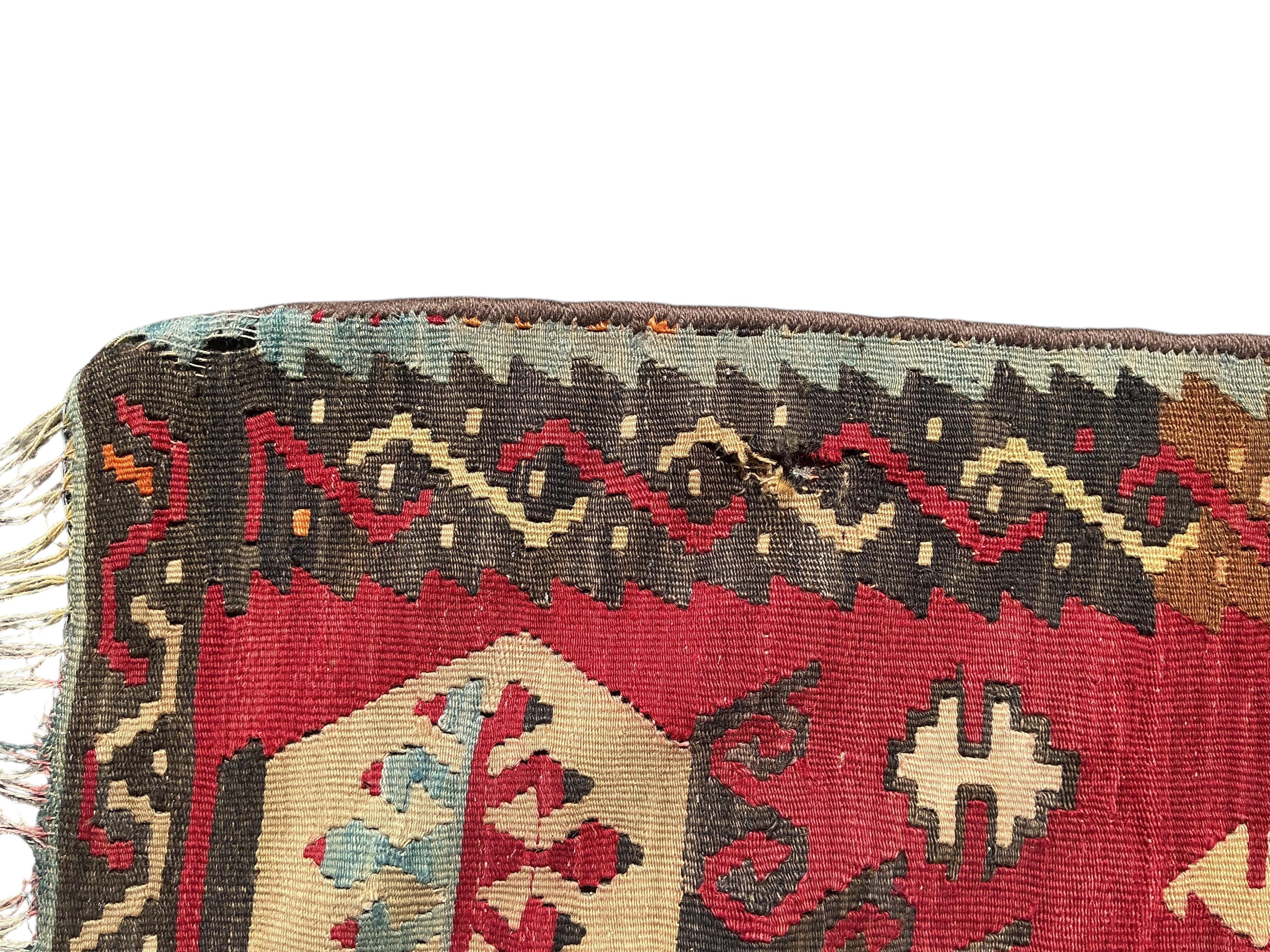 A Turkish Anatolian Kilim polychrome flatweave carpet, woven with geometric lozenges, on a pink field, 350 x 273cm